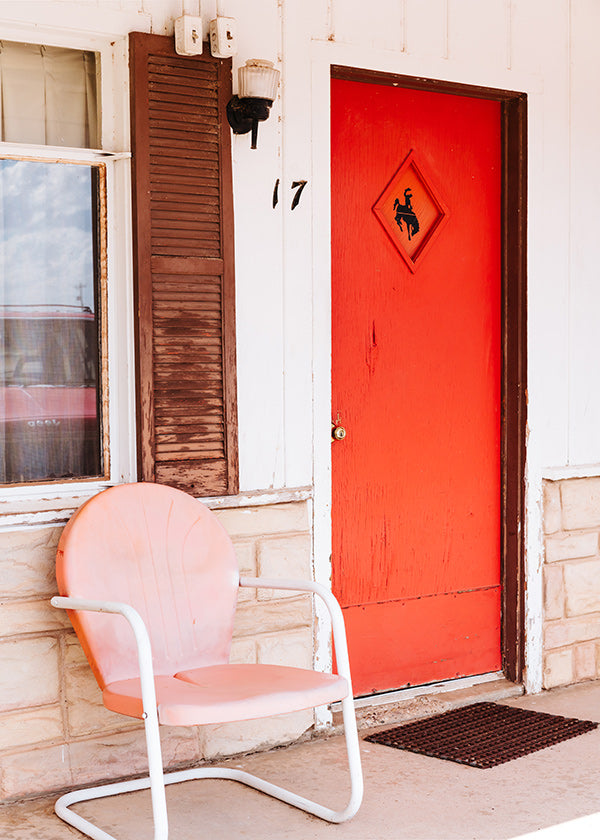 Fotografía de motel con puerta roja y silla retro